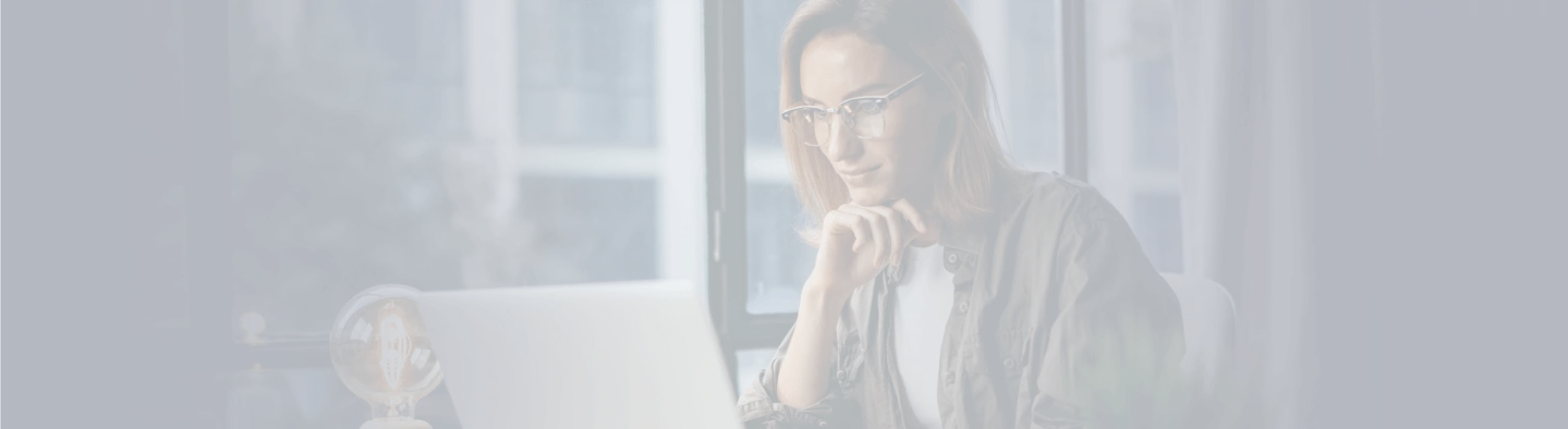Mulher de óculos com a mão no queixo concentrada na tela do notebook