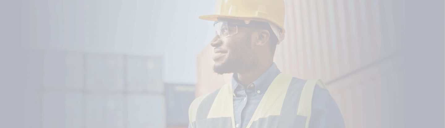 Trabalhador sorridente com capacete e colete reflexivo em área logística