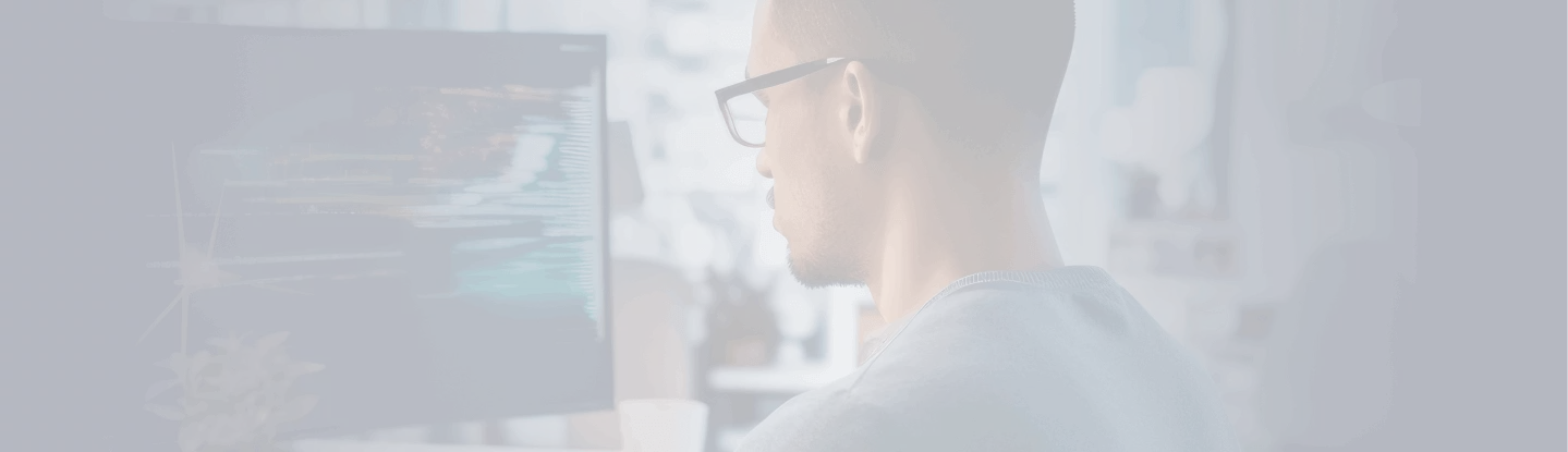 Homem de óculos trabalhando em computador com códigos na tela